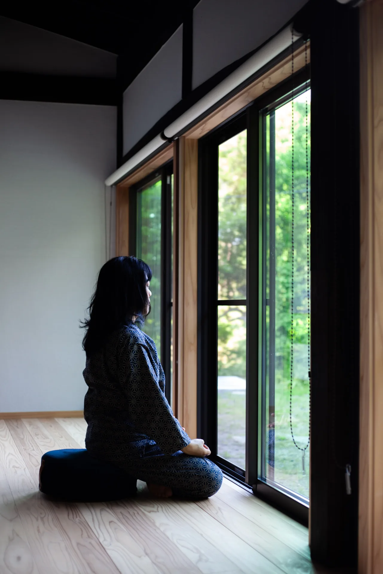 窓辺で里山の緑を眺めるホストのKeiko